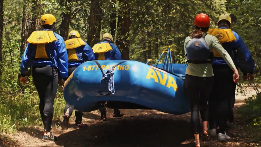 Crew carrying a raft toward the river.